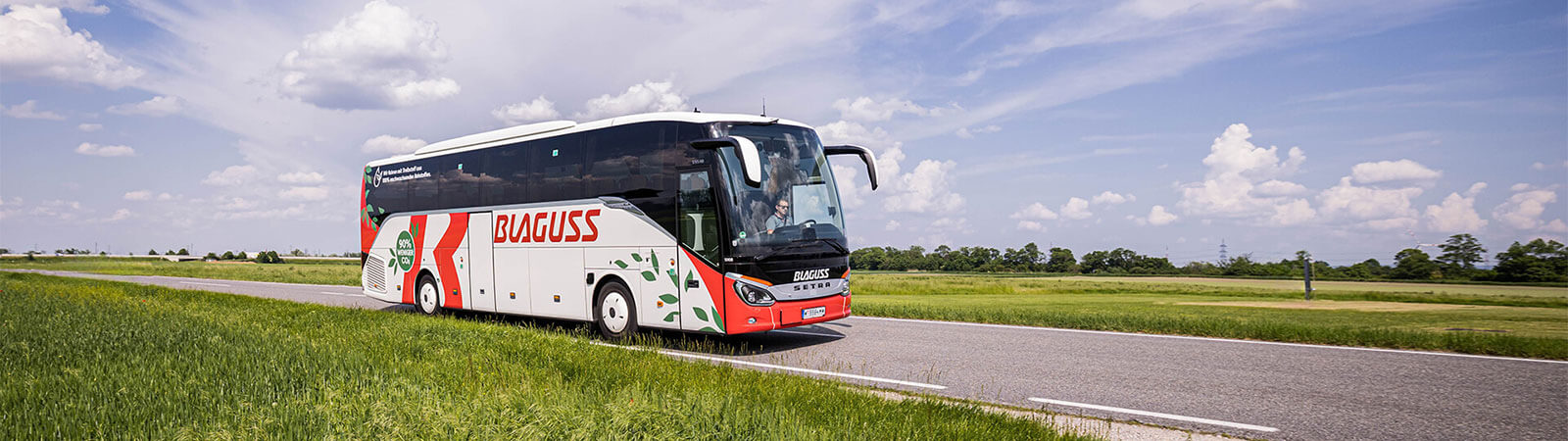 Reisende führen eine Unterhaltung. Im Hintergrund steht ein Lenker und ein Bus.